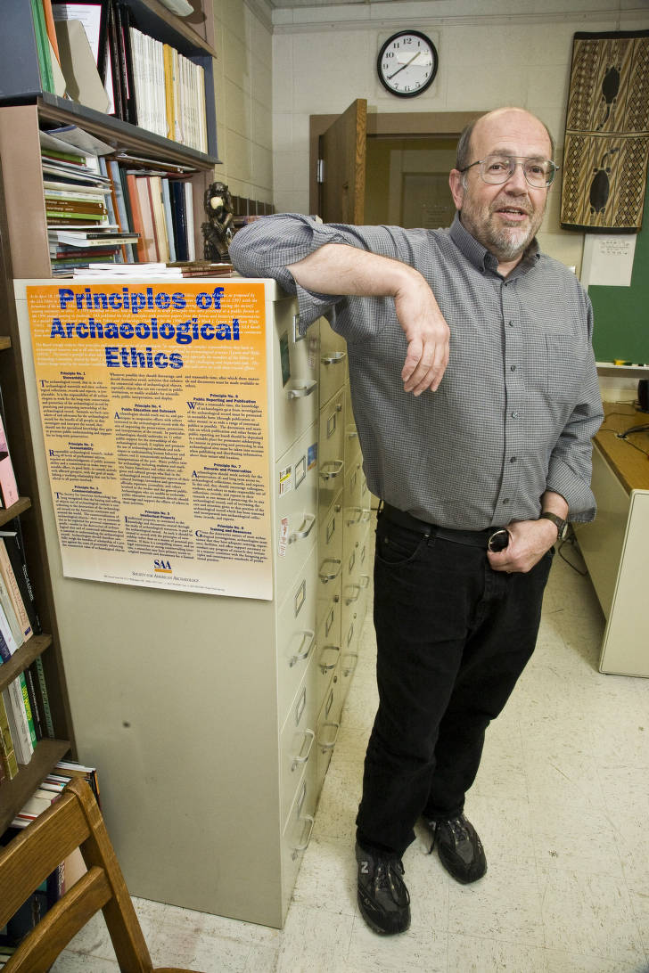 Larry Zimmerman in IUPUI office, SAA Principles of Archaeological Ethics attached to file cabinet